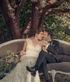 Bride and groom on a vintage sofa under the trees at Akasha Farm