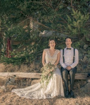 Bride and groom seated on a log in the forest at Akasha Farm