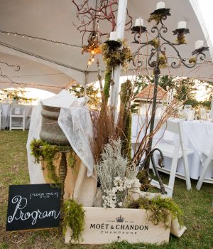 Wedding tent decor with candles and a program sign at Akasha Farm